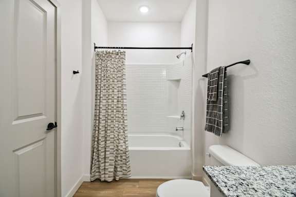 a bathroom with a shower and a toilet and a shower curtain