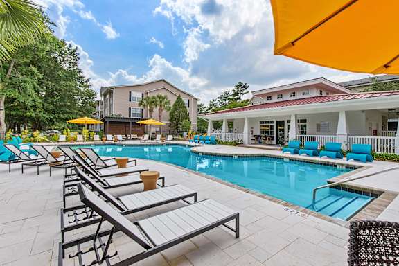 A pool area with sun loungers and a building in the background.