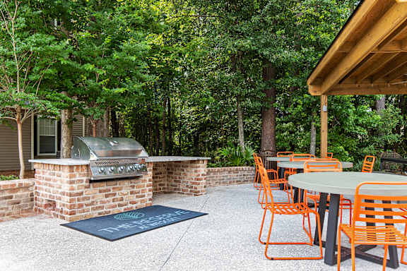 A patio with orange chairs and a grill.