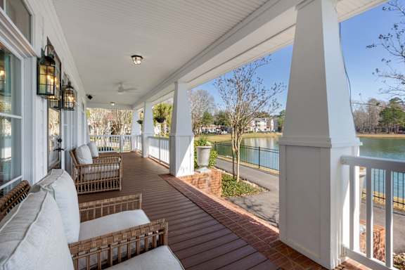 A white porch with a white couch and a white pillow.