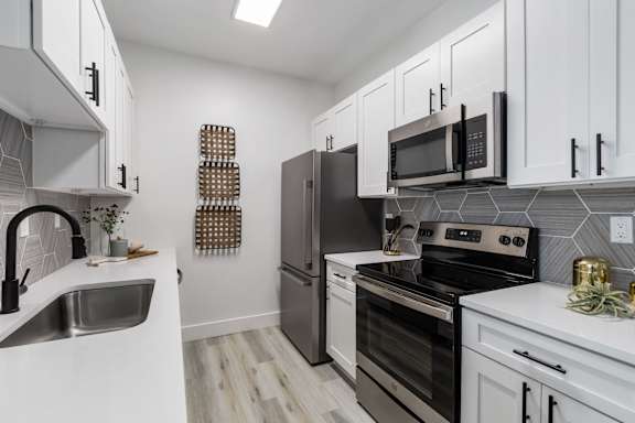 A kitchen with white cabinets and black appliances.