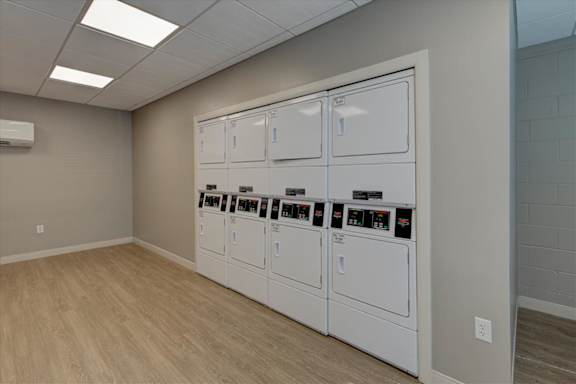 A row of white vending machines are lined up against a wall.