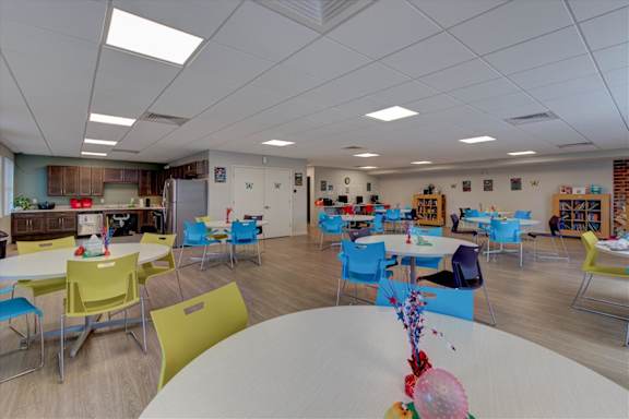 A room with tables and chairs and a white table in the foreground.