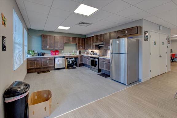 A kitchen with a refrigerator, sink, and cabinets.