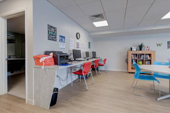 A room with a whiteboard, chairs, and a bookshelf.