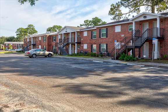 A car is parked on a street in front of apartment buildings.
