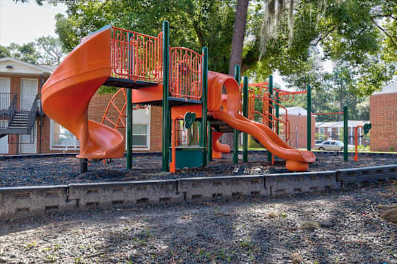 A bright orange slide in a playground.