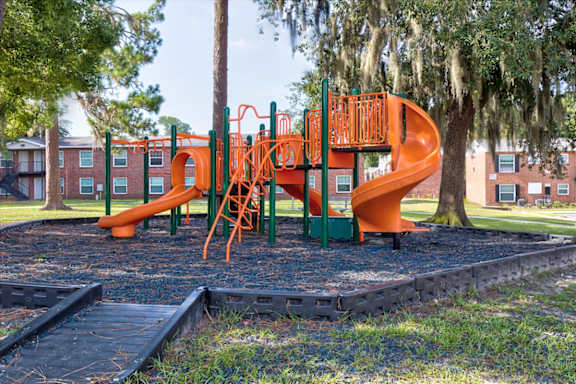 A playground with a green and orange slide.
