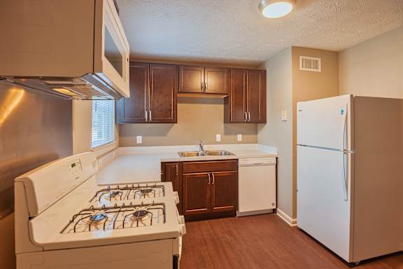 A kitchen with a white stove and a white refrigerator.