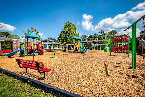 A playground with a red bench and a blue slide.