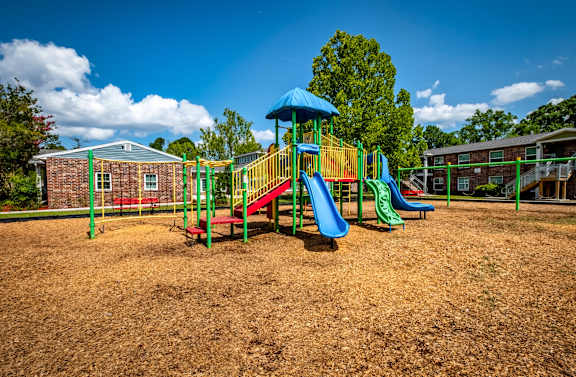 A playground with a blue slide and red and green play structures.