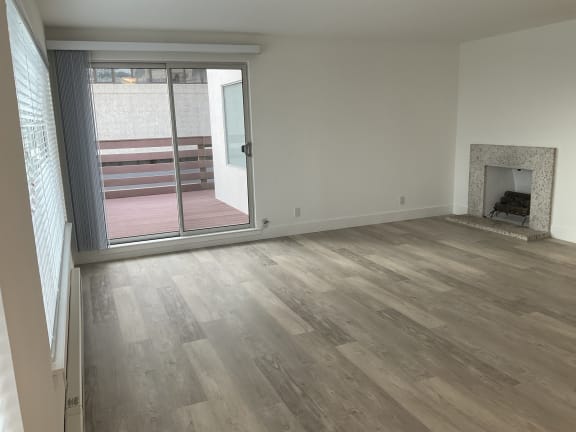 an empty living room with a fireplace and a balcony