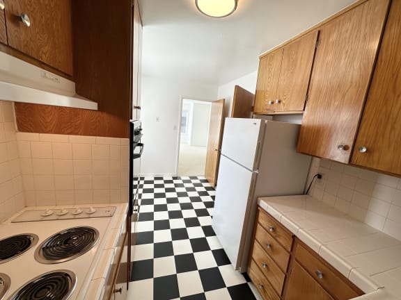 a small kitchen with white appliances and a black and white checkered floor