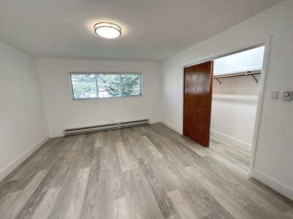 a bedroom with hardwood floors and white walls