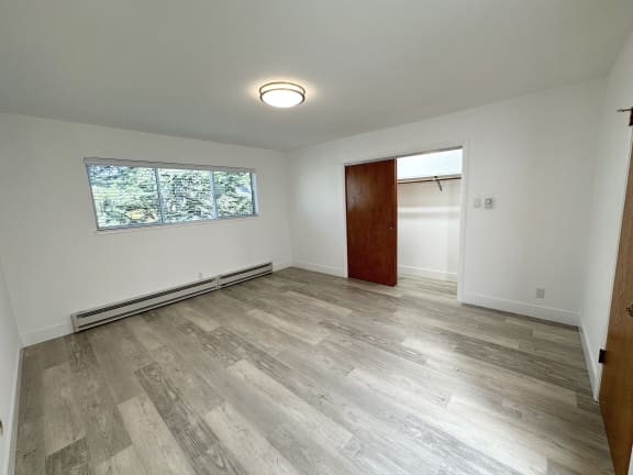 a bedroom with hardwood floors and white walls