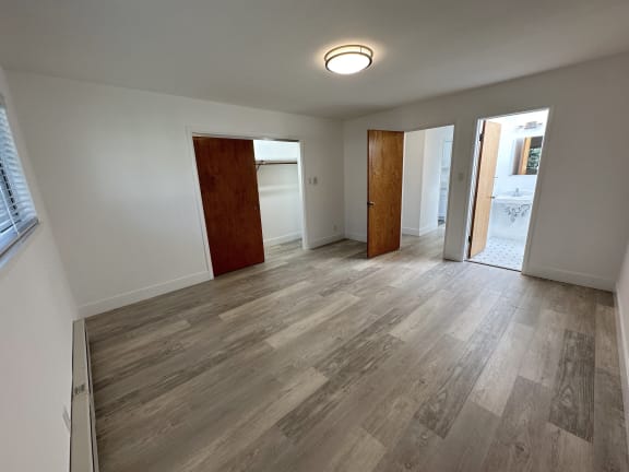 a bedroom with hardwood floors and white walls