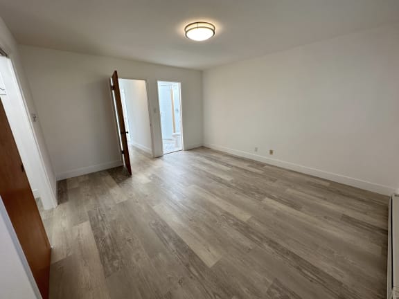 a bedroom with hardwood floors and white walls