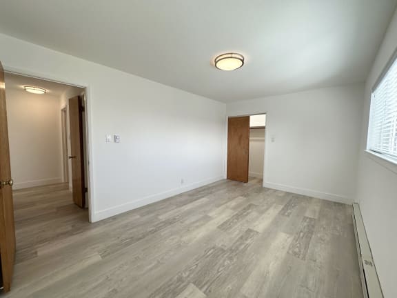 a bedroom with hardwood floors and white walls