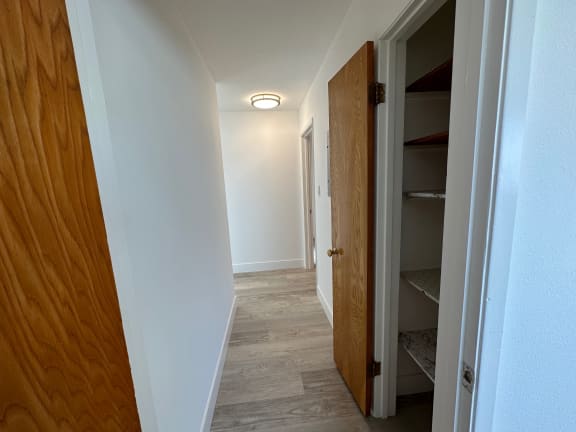 a corridor with a wooden door and white walls
