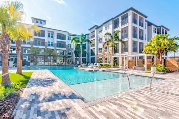 Resort-style pool with expansive sundeck and pergolas at at Tapestry Nona Apartments in Orlando, FL