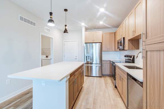 A kitchen with wooden cabinets and a white island.