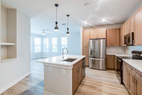 A kitchen with wooden cabinets and a white island at Tapestry Nona Apartments in Orlando, FL