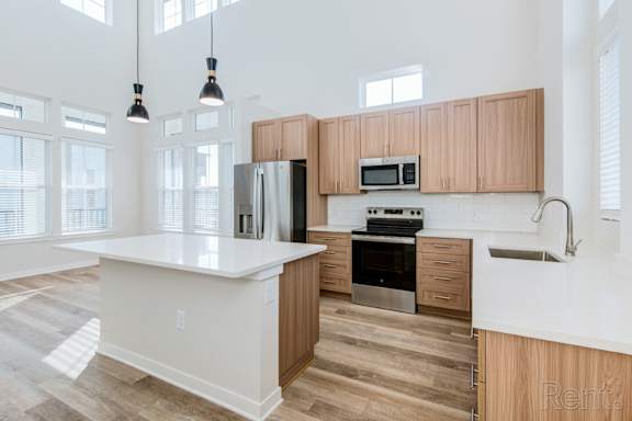 Island kitchen with natural light, quartz countertops, and undermount sink at Tapestry Nona Apartments in Orlando, FL