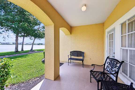 A patio with a black bench and a window with blinds.