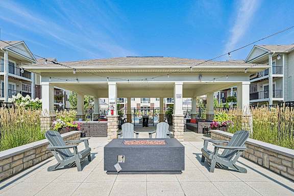 A patio with a fire pit and chairs.