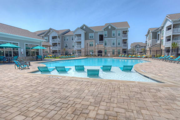 a resort style swimming pool with chaise lounge chairs and umbrellas