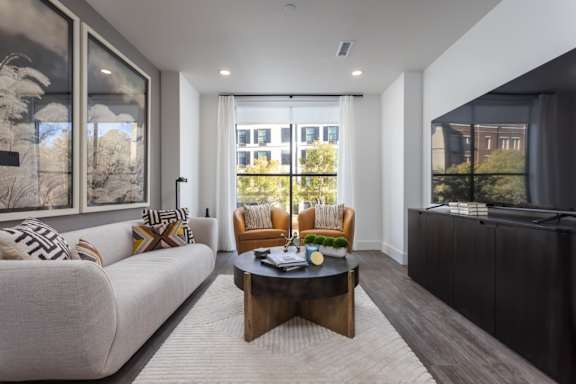 Modern living room with oversized windows, plank flooring, and premium lighting at 2020 Providence in Huntsville, AL