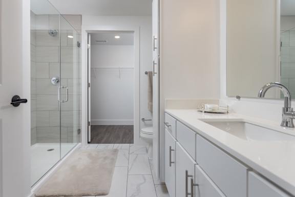 Primary bathroom with modern glass stand-alone shower and quartz countertops at 2020 Providence in Huntsville, AL
