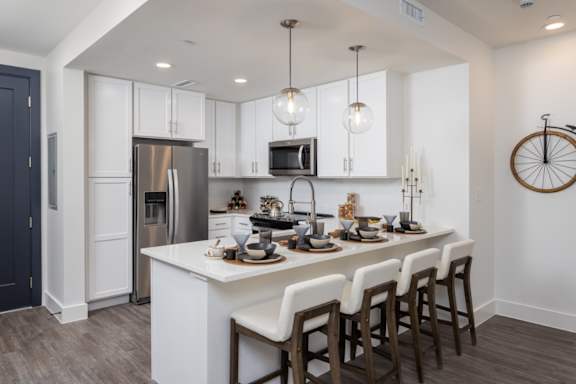 A modern kitchen with a white island and dark wood floors at 2020 Providence in Huntsville, AL