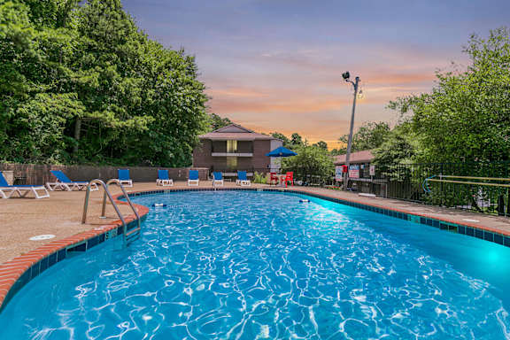 A swimming pool surrounded by trees and lounge chairs at Arbor Pointe at Hillcrest in Little Rock, AR