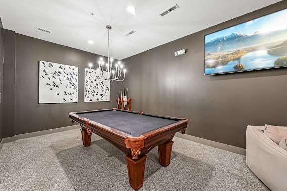 A pool table in a room with a painting on the wall and a sofa.