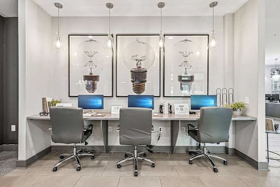 A modern office with grey chairs and desks, and hanging light bulb decorations.