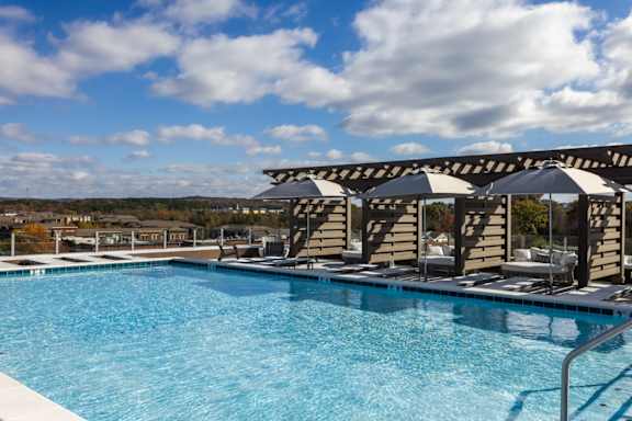 A swimming pool with a metal railing and umbrellas at 2020 Providence in Huntsville, AL
