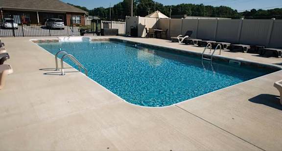 A large swimming pool with a concrete floor and a metal ladder.