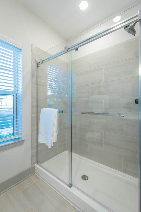 Anthem Apartments a shower with a glass door and tile floors and walls