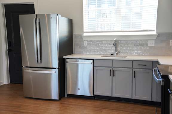 A kitchen with a stainless steel appliances, large window, and undermount sink at West Row Lofts and Townhomes in Birmingham, AL