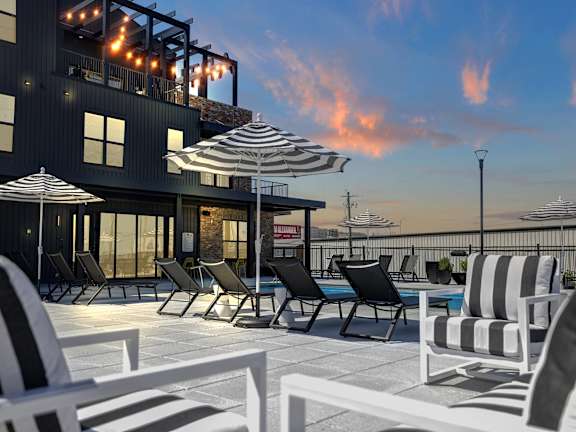 Pool Deck and Seating with Umbrellas at Artisan Flats Apartments in Birmingham, AL an outdoor patio with chairs and umbrellas at dusk at Artisan Flats in Birmingham, AL