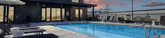 the pool is next to a building with umbrellas at Artisan Flats in Birmingham, AL