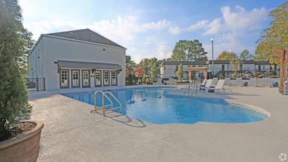 A pool with a diving board and a building in the background.
