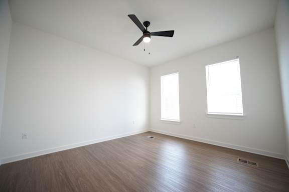 A bedroom with a ceiling fan and two windows at Wesley Place Apartments in Birmingham, AL