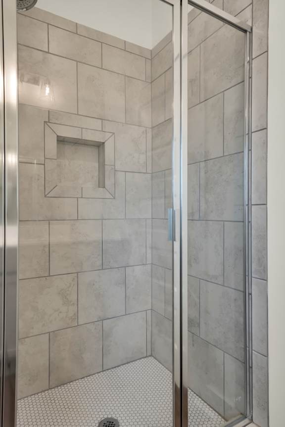 A shower with a glass door and a tiled wall at Turnberry Park Luxury Rental Homes