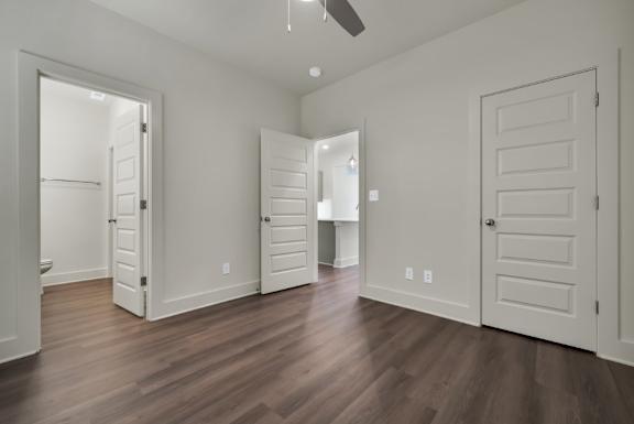 A room with white walls and wooden floors with a ceiling fan at Turnberry Park Luxury Rental Homes.