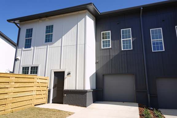 Townhouse building exterior with attached garage and fenced pet yard at Wesley Place Apartments in Birmingham, AL