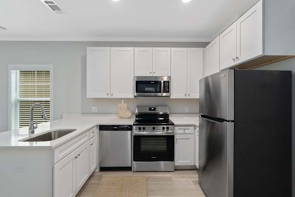 an all white kitchen with stainless steel appliances and white cabinets