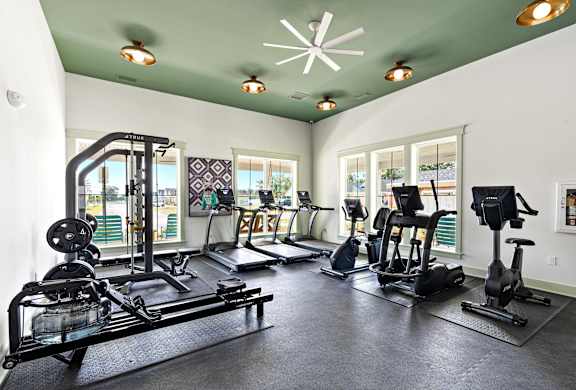 the gym has plenty of exercise equipment and windows