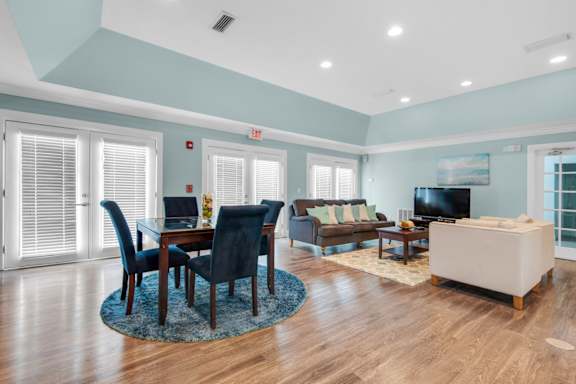 A modern clubhouse with tables and a lounge area with a TV at Crystal Lake in Pensacola, Florida.